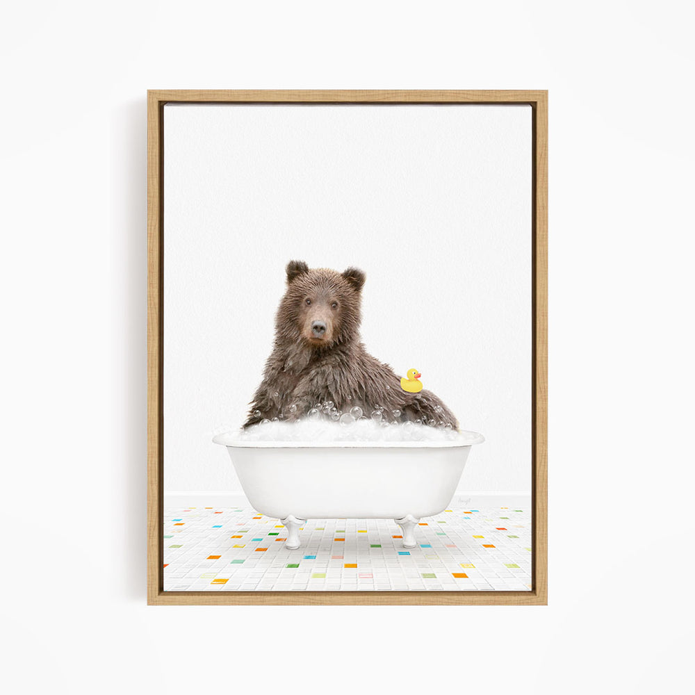 A brown bear sitting in a white bathtub filled with bubbles, with a rubber duck floating on the water.