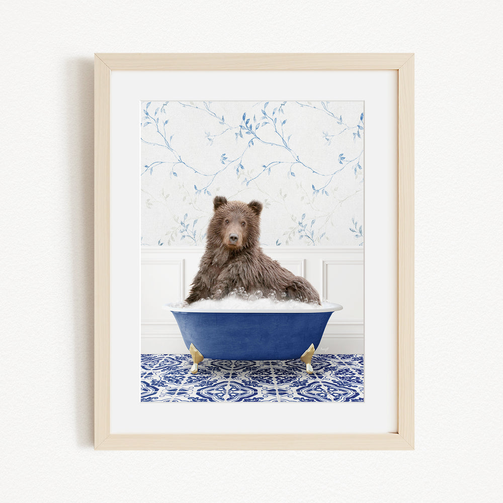A brown bear sitting in a blue bathtub filled with bubbles, with a patterned tile floor and a floral wallpaper in the background.