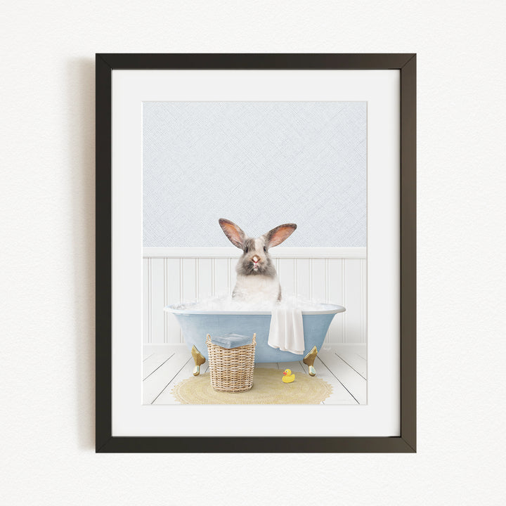 A white rabbit sitting in a blue bathtub filled with water, surrounded by a yellow rubber duck and a basket.