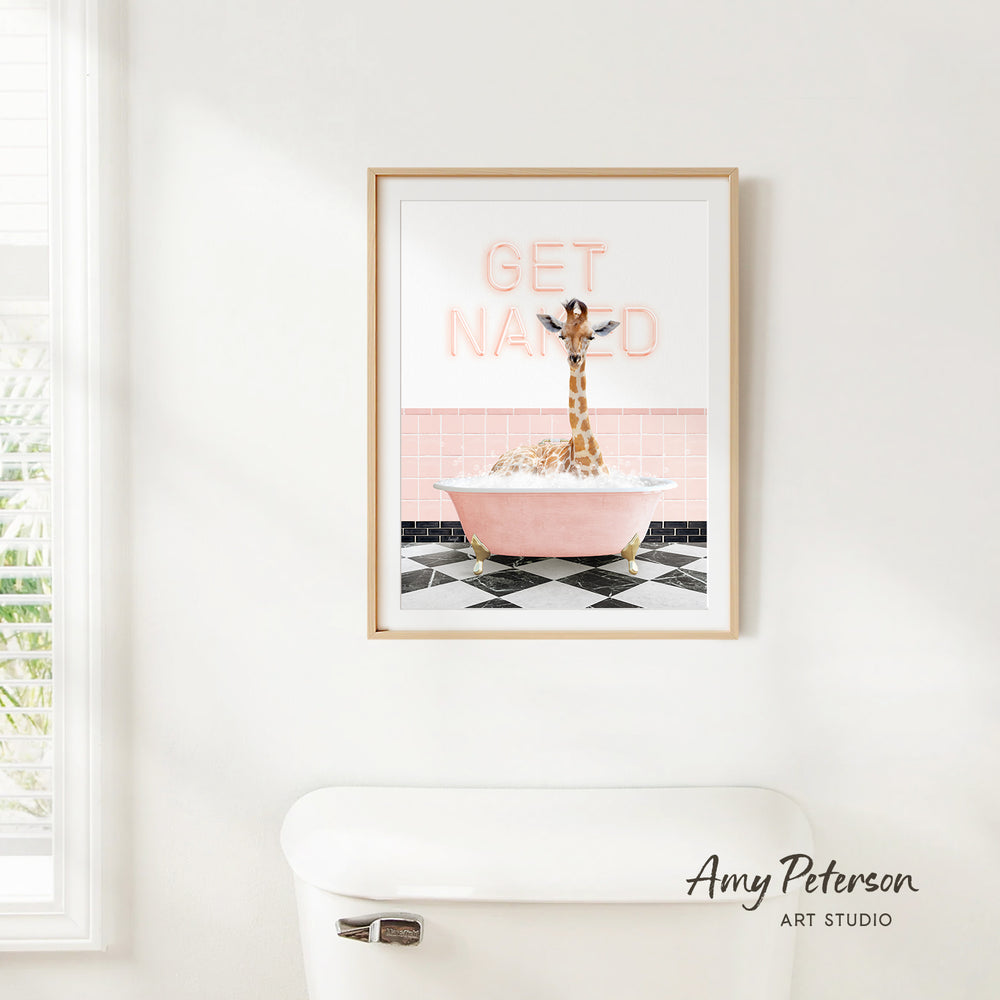 A framed print of a giraffe sitting in a pink bathtub with the text "GET NANED" on it, hanging on a white wall.