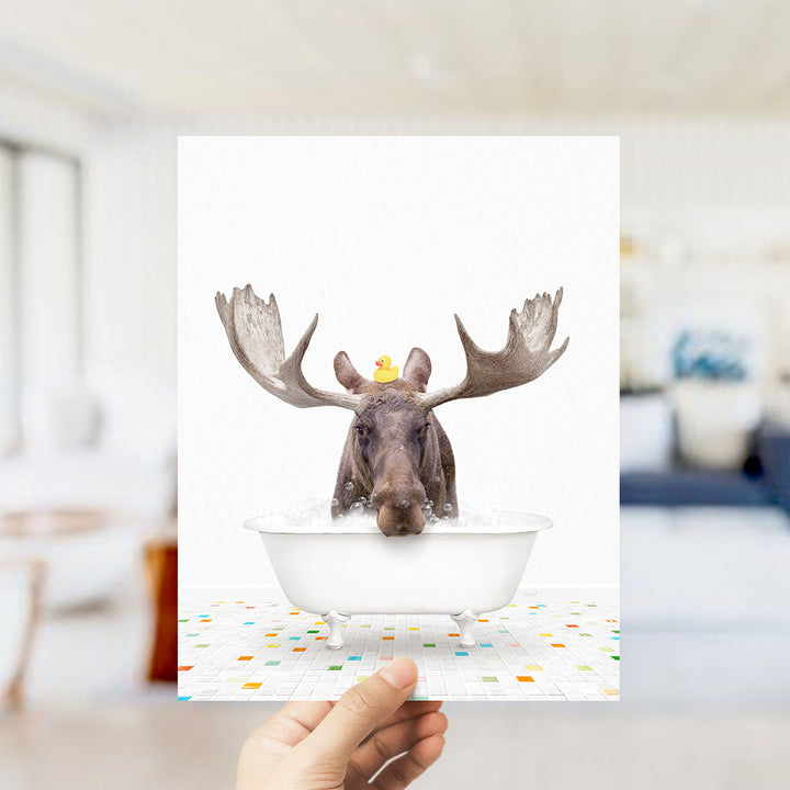 A moose with large antlers is sitting in a bathtub filled with water, with a yellow rubber duck floating on its head.