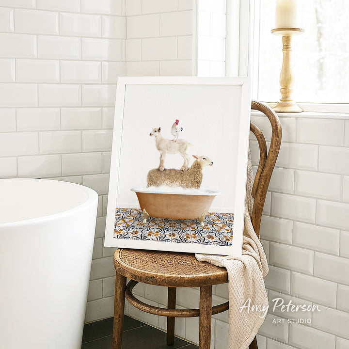 A framed image of a sheep standing on a chicken in a bathtub, placed on a wooden chair in a bathroom setting.