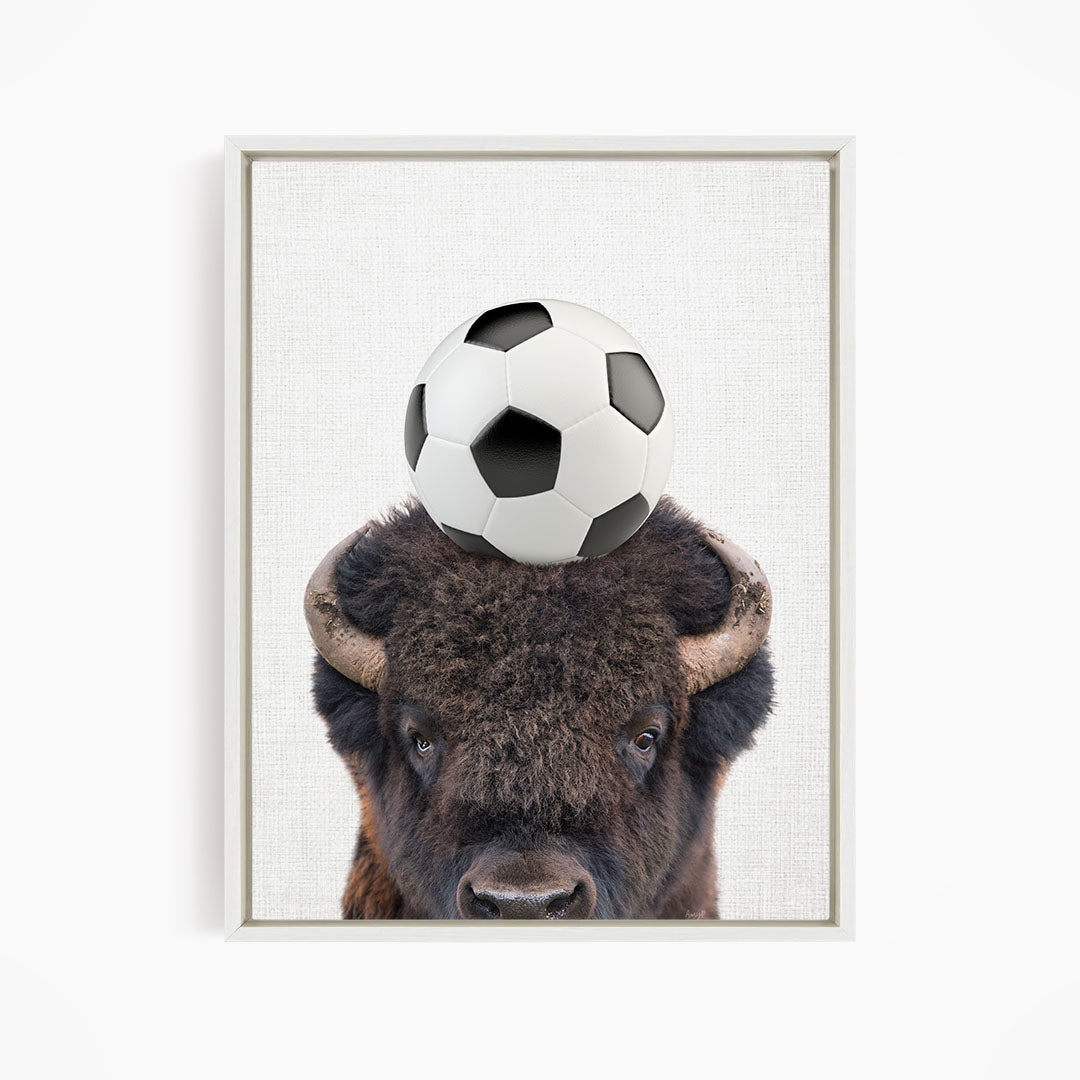 A buffalo with a soccer ball on its head.