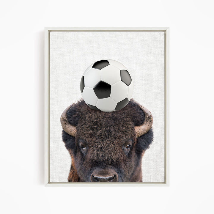 A buffalo with a soccer ball on its head.