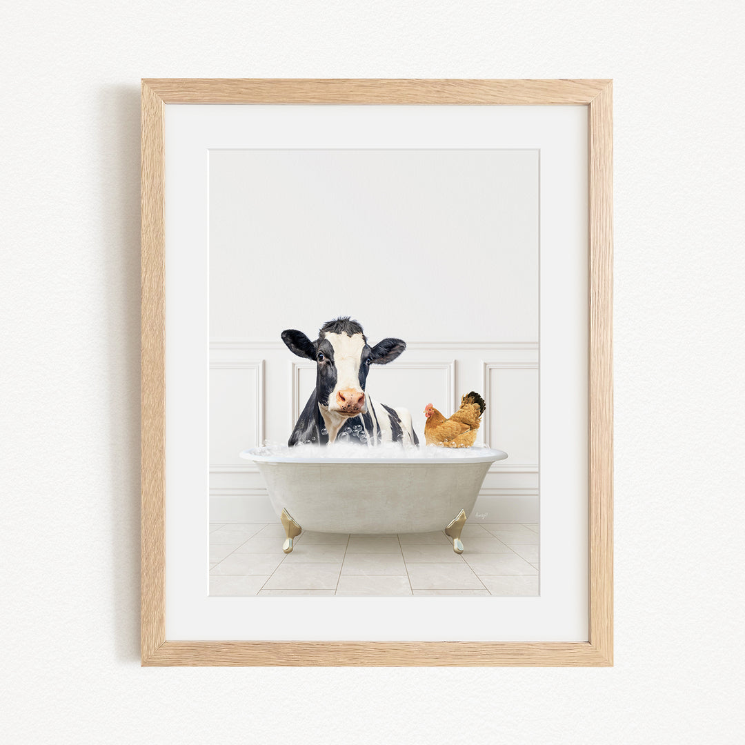 A black and white cow is sitting in a white bathtub, with a chicken standing nearby, in a white-walled room.