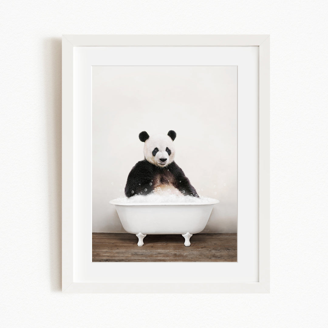 A panda bear sitting in a white bathtub filled with bubbles, looking directly at the camera.