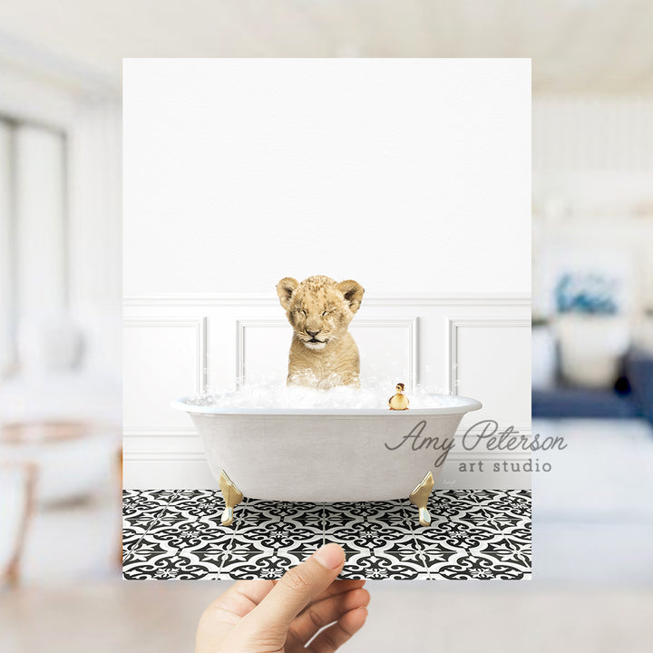 a hand holding a card with a picture of a baby lion in a bathtub