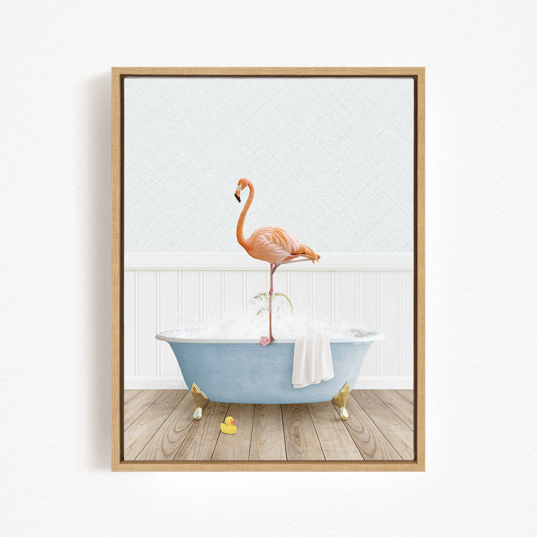 A framed image depicting a pink flamingo standing on one leg inside a blue bathtub filled with water and bubbles.