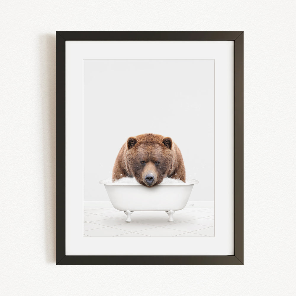 A brown bear is sitting in a white bathtub, appearing to be enjoying a relaxing bath.