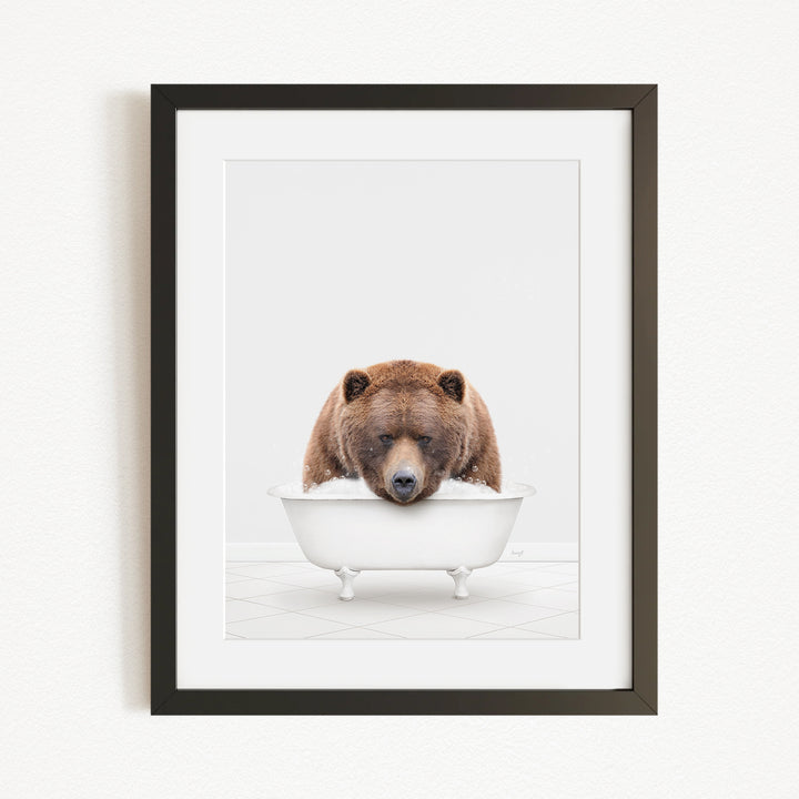 A brown bear is sitting in a white bathtub, appearing to be enjoying a relaxing bath.