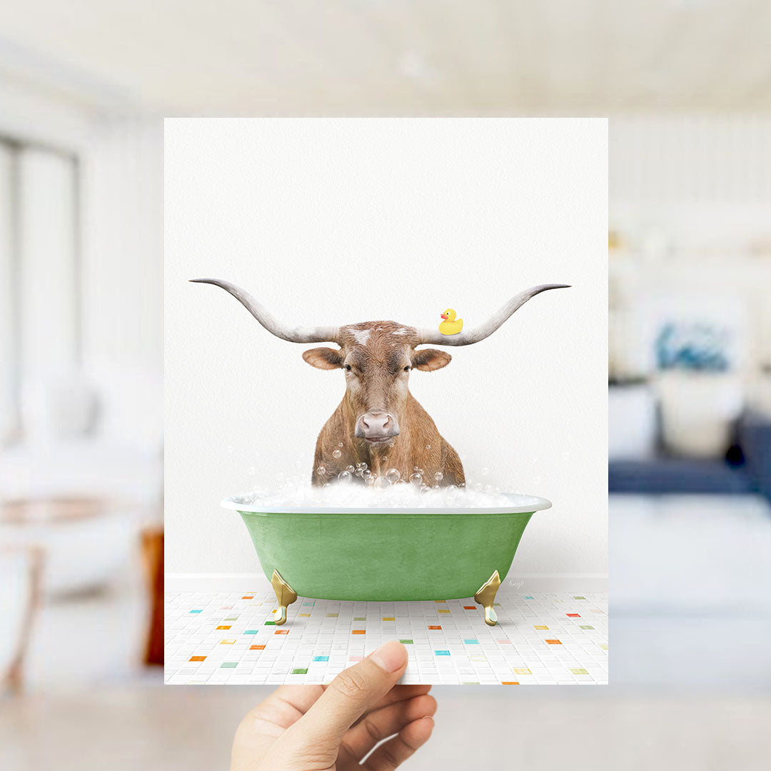 A brown cow with large horns is sitting in a green bathtub filled with bubbles, with a yellow rubber duck floating on its head.