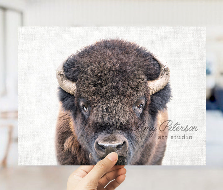 a hand holding up a picture of a bison