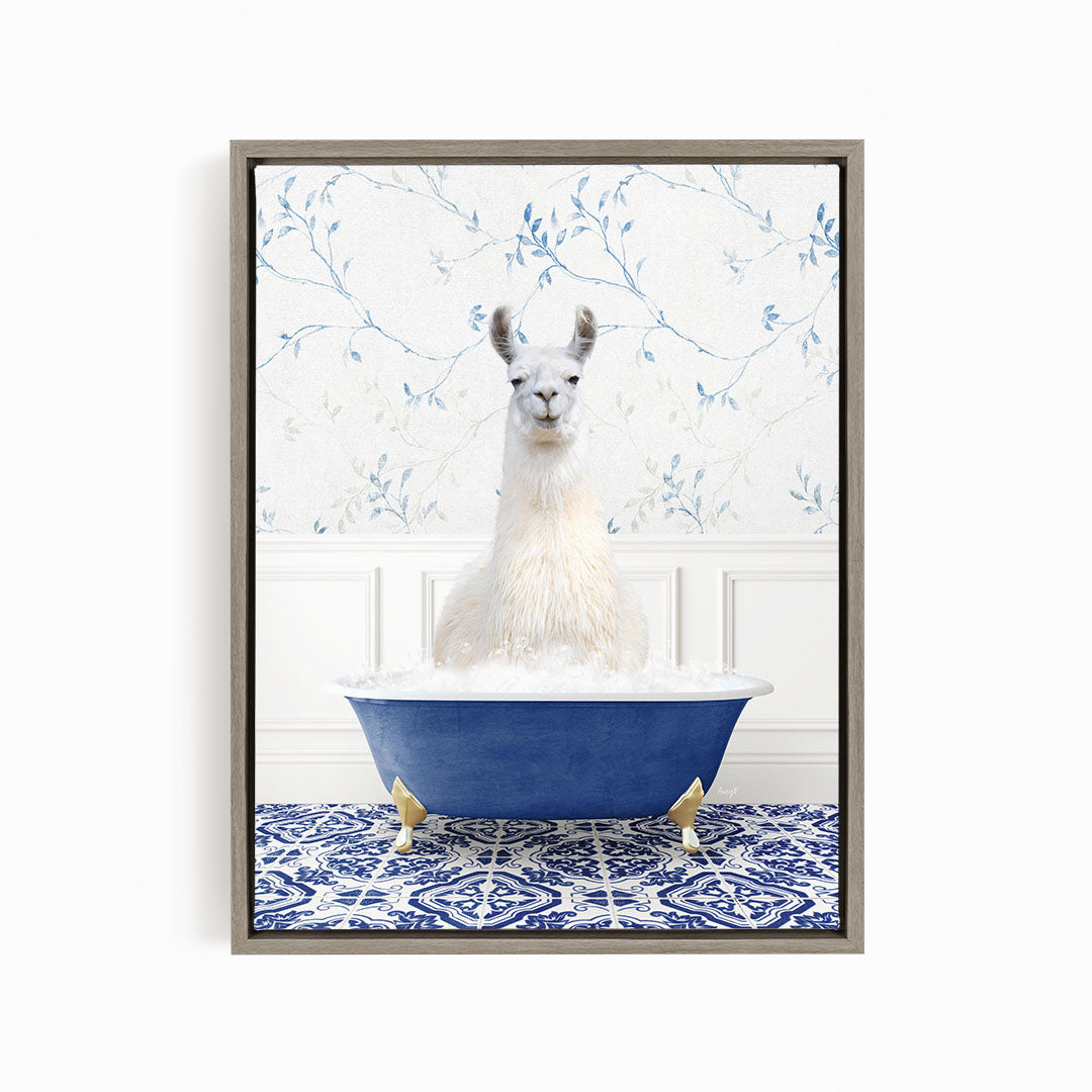 A white llama sitting in a blue bathtub filled with bubbles, surrounded by a blue and white patterned rug.