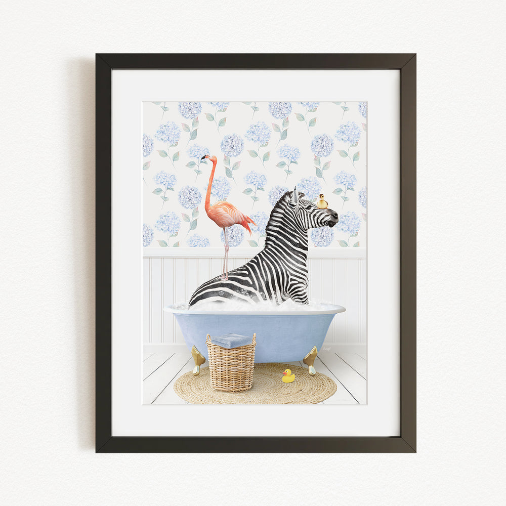 A framed image depicting a zebra sitting in a bathtub, with a flamingo standing on its back and a basket of rubber ducks nearby.
