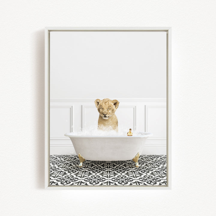 A young lion cub is sitting in a white bathtub filled with bubbles, surrounded by a black and white patterned floor.