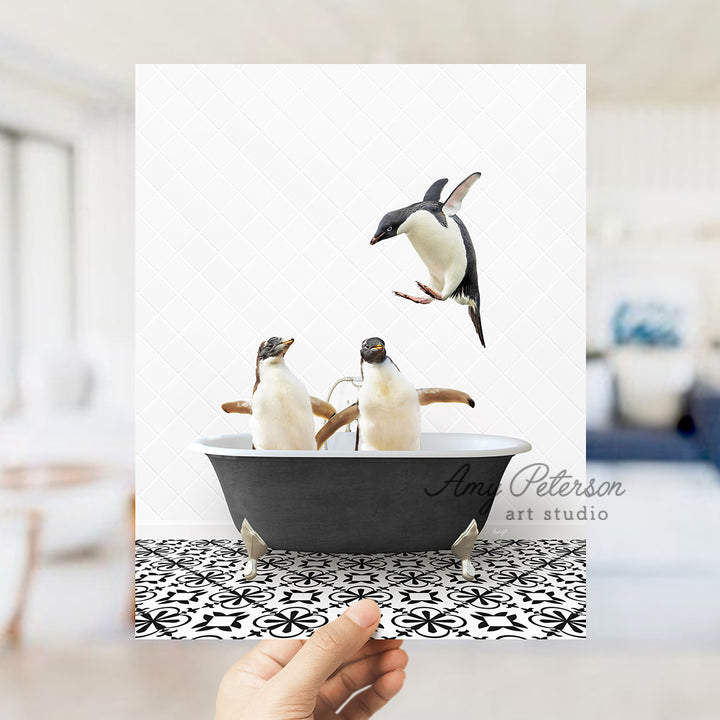 a hand holding a card with three penguins in a bathtub