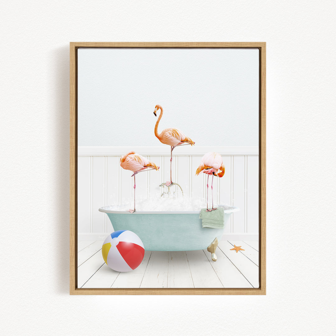 A framed image depicting three flamingos standing in a bathtub filled with bubbles, with a beach ball and starfish nearby.