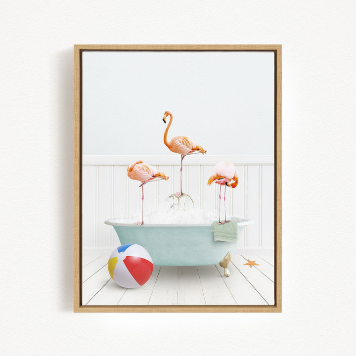 A framed image depicting three flamingos standing in a bathtub filled with bubbles, with a beach ball and starfish nearby.