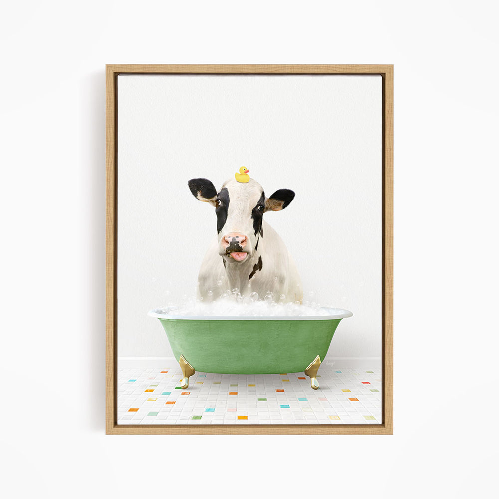 A black and white cow is sitting in a green bathtub filled with bubbles, with a rubber duck perched on its head.