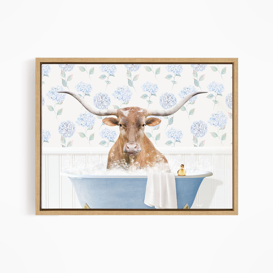 A brown cow with large horns is sitting in a blue bathtub filled with water, surrounded by a floral patterned wall.