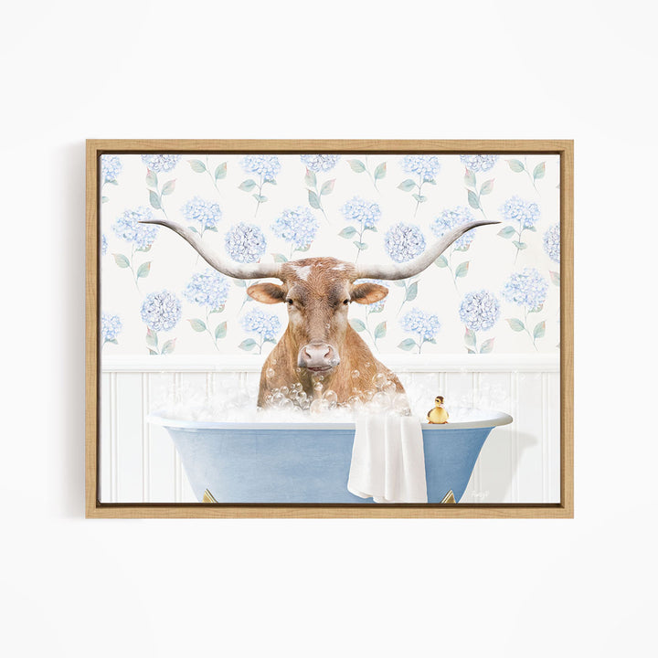 A brown cow with large horns is sitting in a blue bathtub filled with water, surrounded by a floral patterned wall.