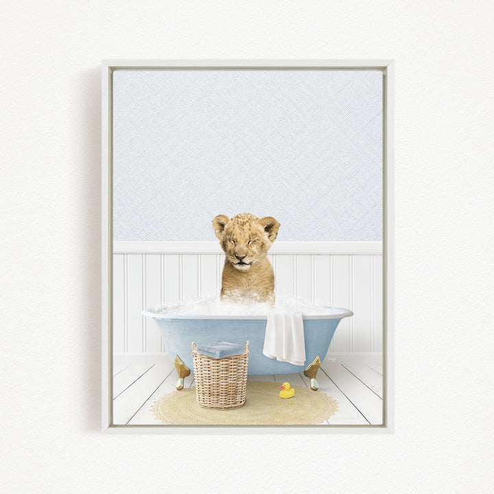 A young lion cub sitting in a blue bathtub filled with water, surrounded by a yellow rubber duck and a basket.
