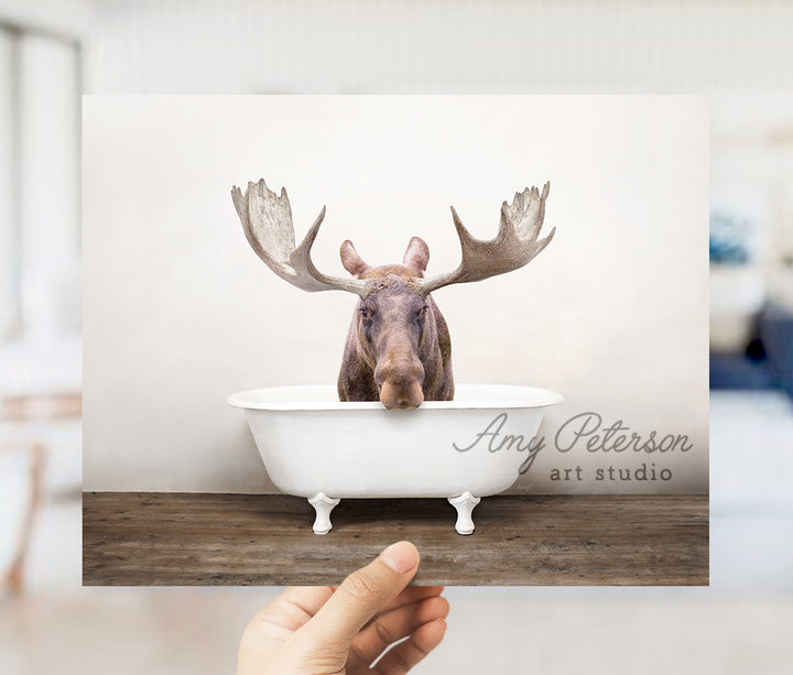 a person holding up a card with a picture of a moose in a bathtub