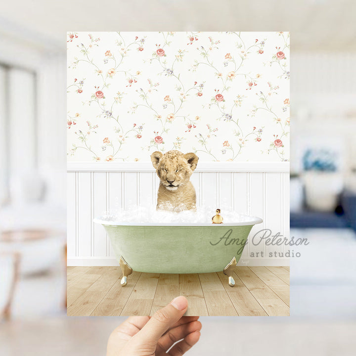 a hand holding up a photo of a baby lion in a bathtub