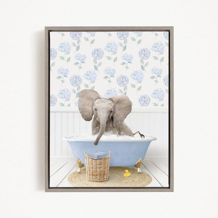 A gray elephant is sitting in a blue bathtub filled with water, surrounded by a wicker basket and a yellow rubber duck.