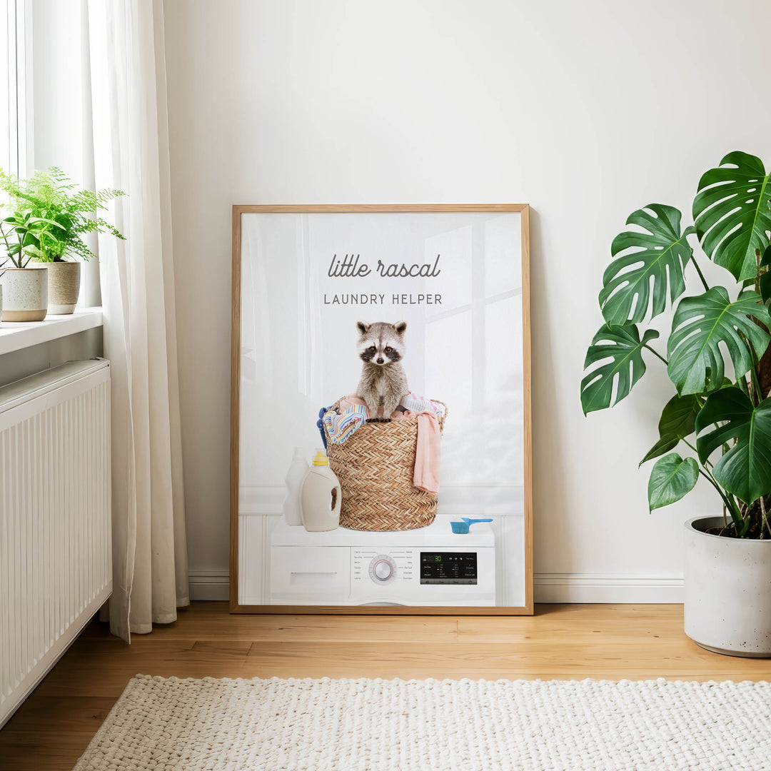 A framed poster featuring a raccoon sitting on a laundry basket, with the text "Little raccal Laundry Helper" on the poster.