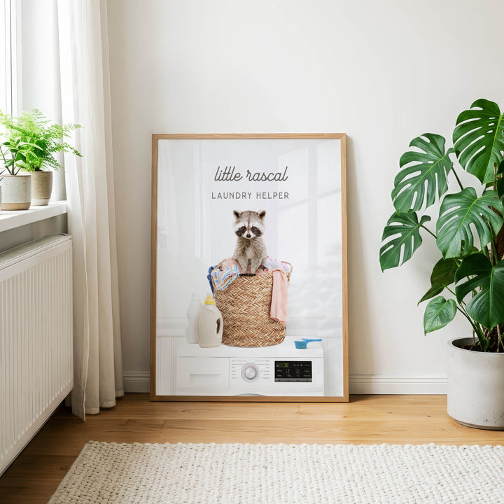 A framed poster featuring a raccoon sitting on a laundry basket, with the text "Little raccal Laundry Helper" on the poster.