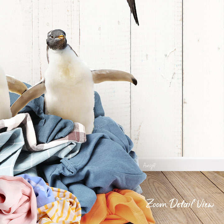 A penguin standing on a pile of clothes, with a wooden wall in the background.