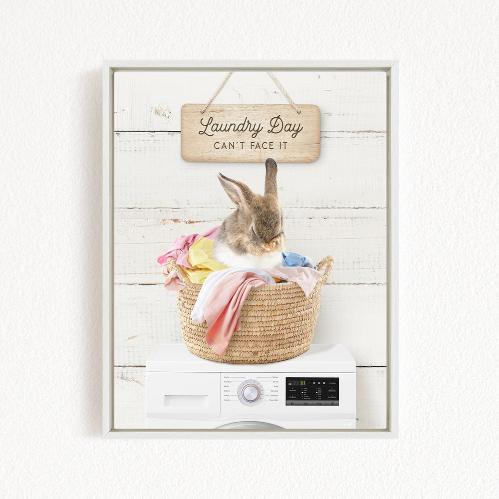 A cute rabbit sitting in a woven laundry basket, with a sign above that says "Laundry Day Can't Face It".