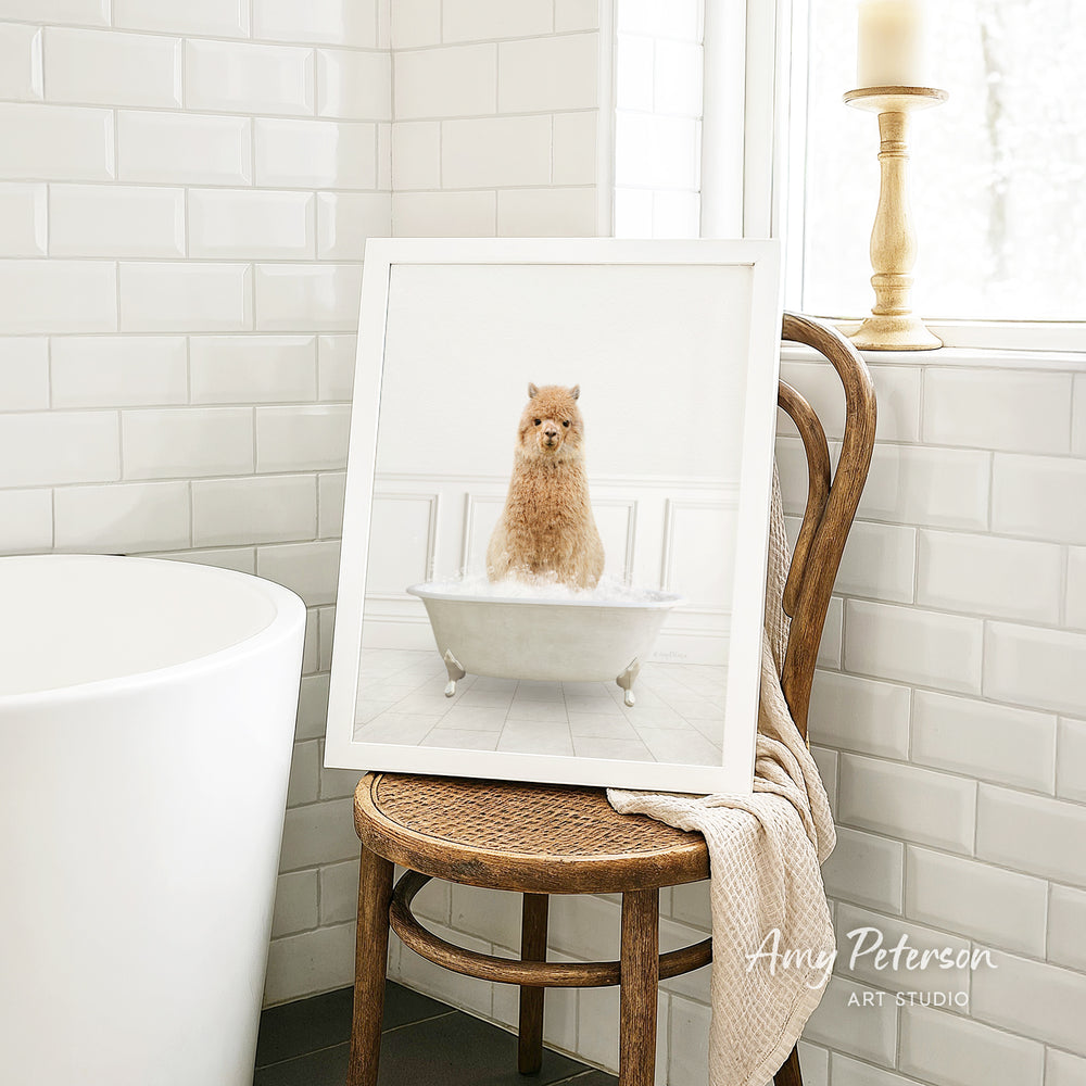 A framed image of a small dog sitting in a bathtub, with a towel draped over the back of a wooden chair in a bathroom setting.