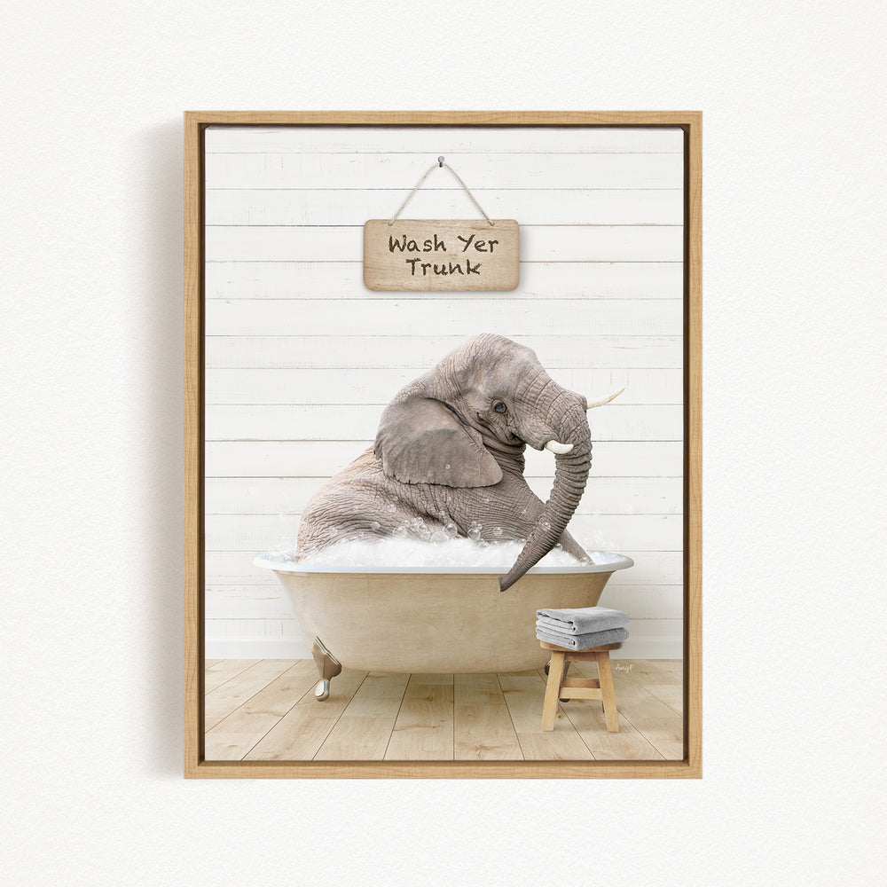 A framed image depicting an elephant sitting in a bathtub, with a sign above that says "Wash Yer Trunk".