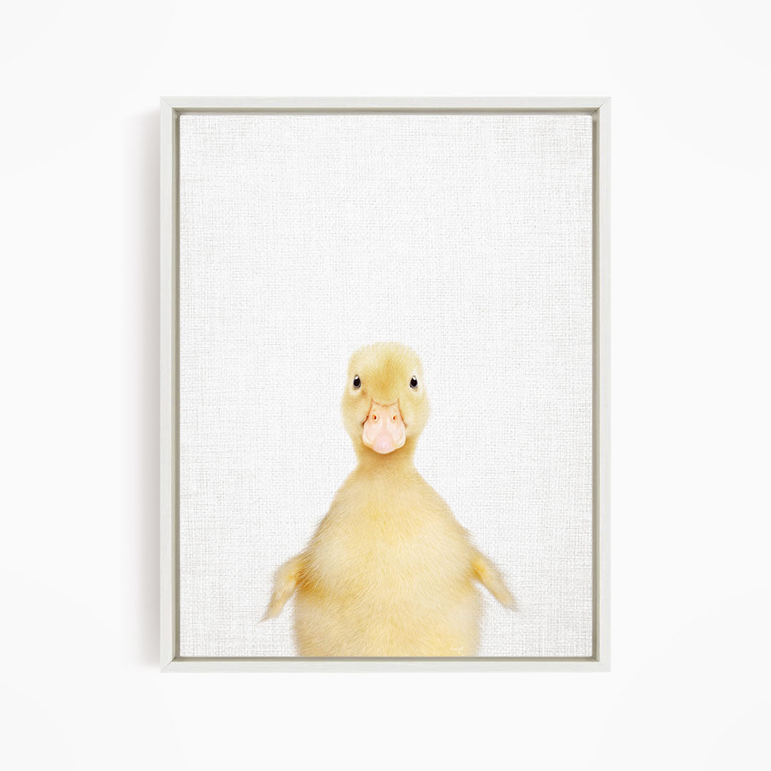 A cute yellow duck with a pink beak and eyes is looking directly at the camera.