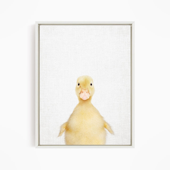 A cute yellow duck with a pink beak and eyes is looking directly at the camera.