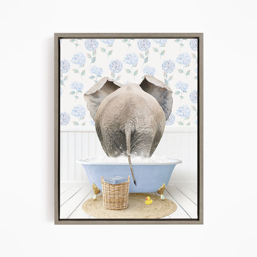 An elephant is taking a bath in a blue tub, surrounded by a wicker basket and rubber ducks, with a floral patterned wall in the background.