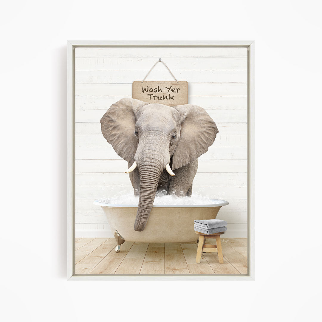 A gray elephant standing in a bathtub filled with water, with a sign above it that says "Wash Yer Trunk".