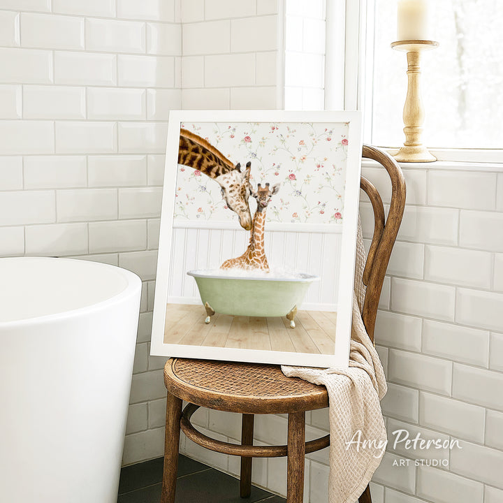 A framed image of two giraffes sitting in a bathtub, with one giraffe appearing to be bathing the other.