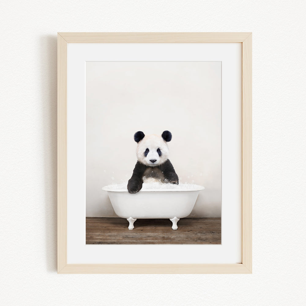 A panda bear sitting in a white bathtub filled with bubbles, looking directly at the camera.