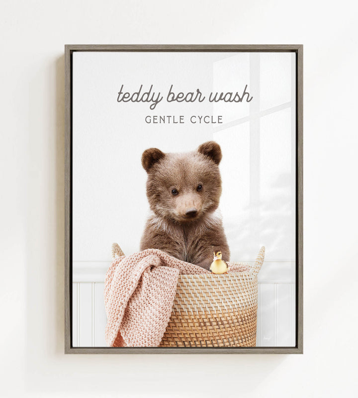 A teddy bear sitting in a woven basket, with a blanket and a toy duck nearby.