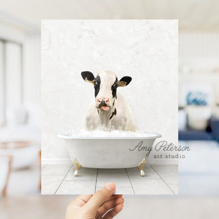 a hand holding up a picture of a cow in a bathtub