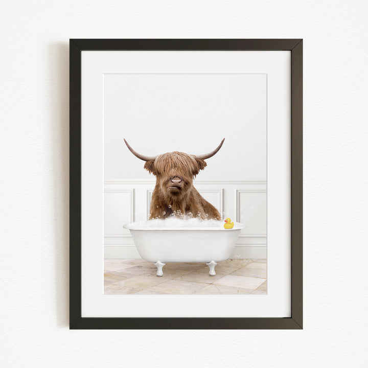 A brown cow with long horns is sitting in a white bathtub filled with water, with a yellow rubber duck floating in the tub.