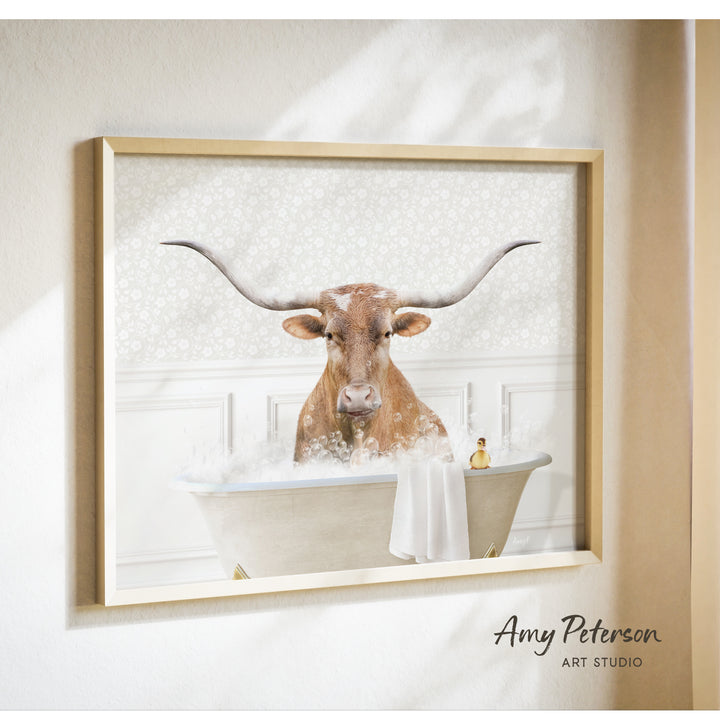 A framed image of a brown cow with large horns sitting in a bathtub filled with bubbles.