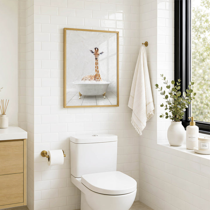 A bathroom with a white toilet, a framed picture of a giraffe in a bathtub, and a window with greenery on the sill.