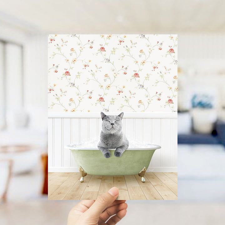 A gray cat sitting in a green bathtub, with a floral wallpaper in the background.