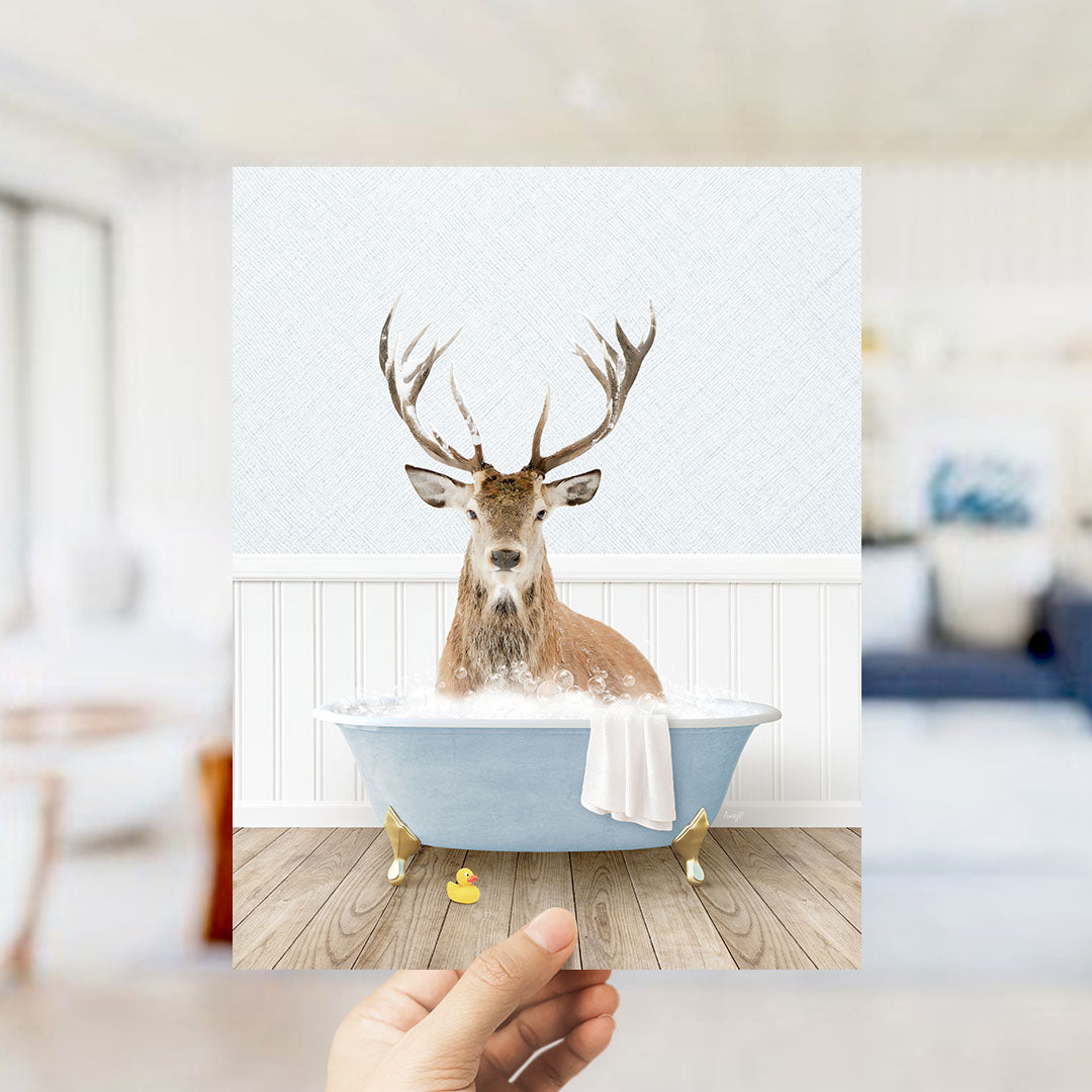 A deer with antlers is sitting in a bathtub filled with water, surrounded by a white interior and a wooden floor.
