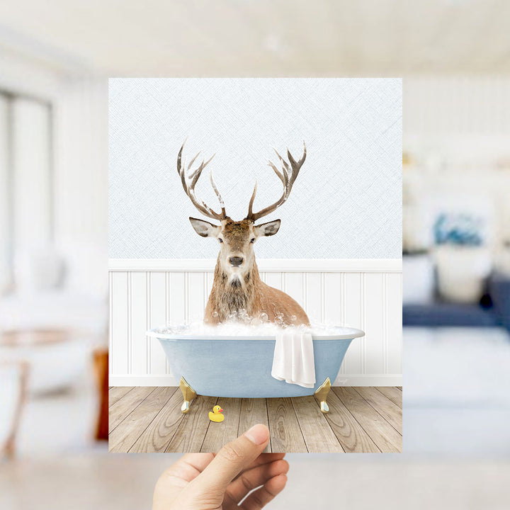 A deer with antlers is sitting in a bathtub filled with water, surrounded by a white interior and a wooden floor.