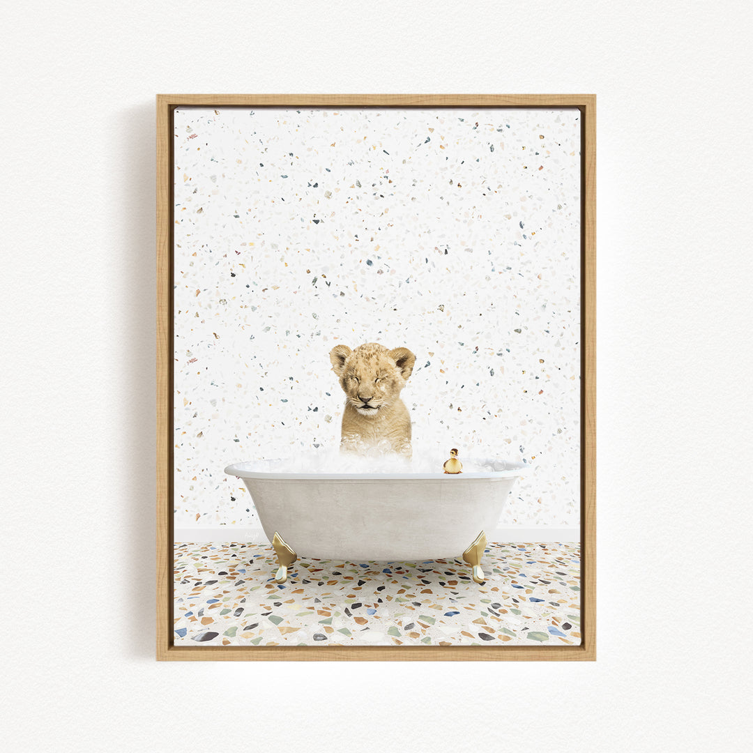 A young lion cub sitting in a white bathtub filled with water, surrounded by a speckled tiled floor.